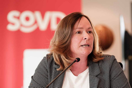 Frau sitzt vor einem SoVD-Logo und spricht in ein Mikrofon.