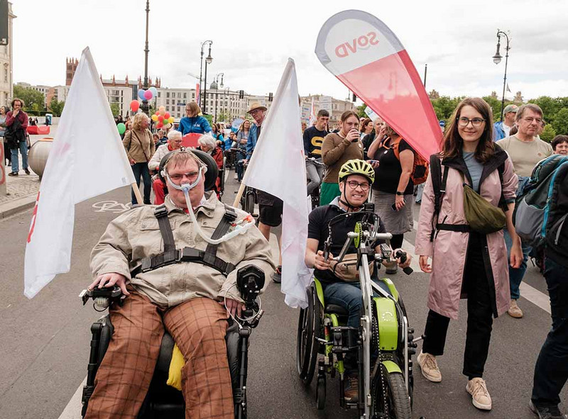 Junger Mann im Rollstuhl mit SoVD-Fahnen.