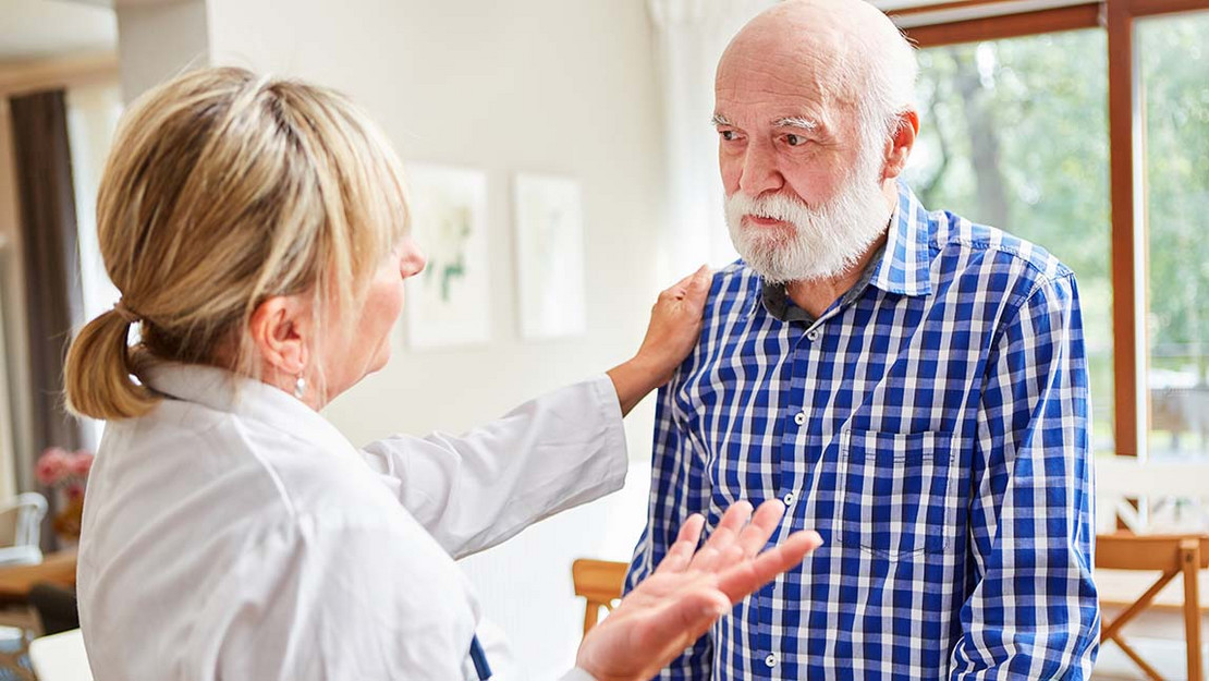 Ärztin spricht mit älterem Patienten. 