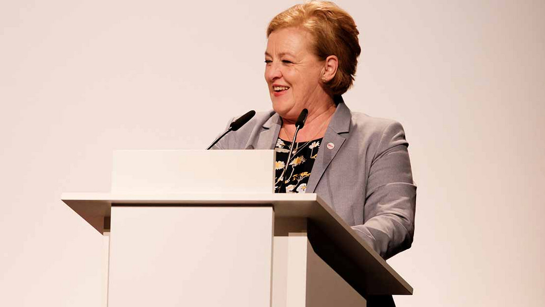 Frau hält Rede am Pult.