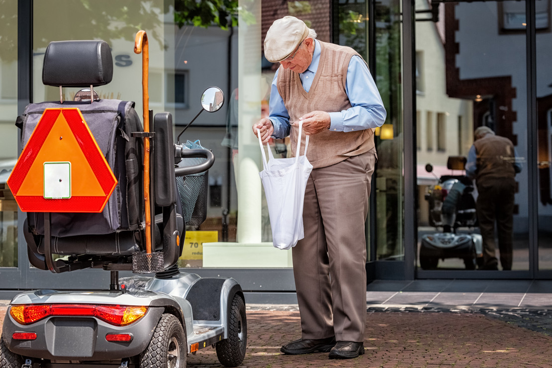 Älterer Mann mit E-Mobil beim Einkauf.