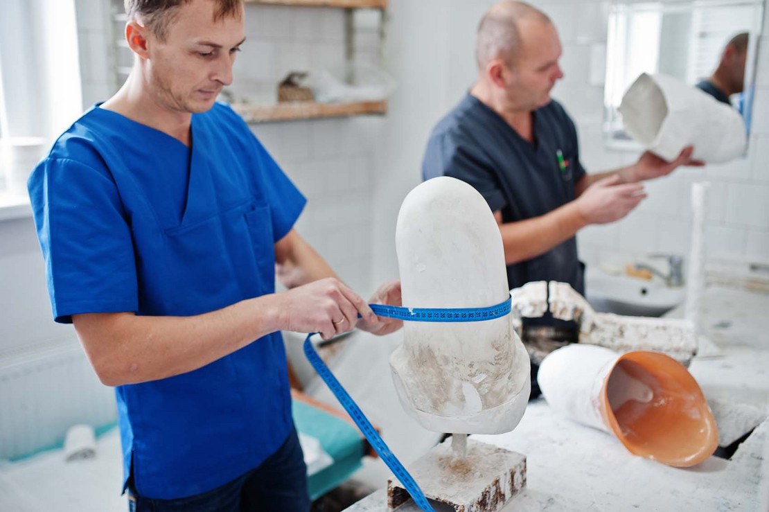 Zwei Männer stellen Prothesen her.