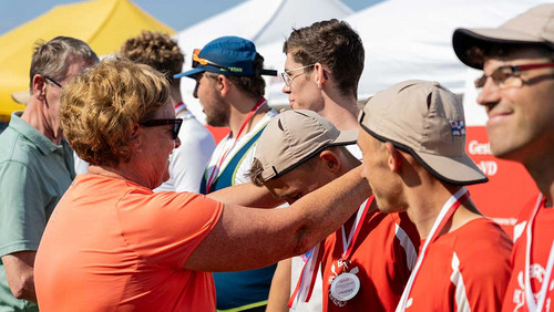 Frau hängt jungem Mann eine Medaille um den Hals. 