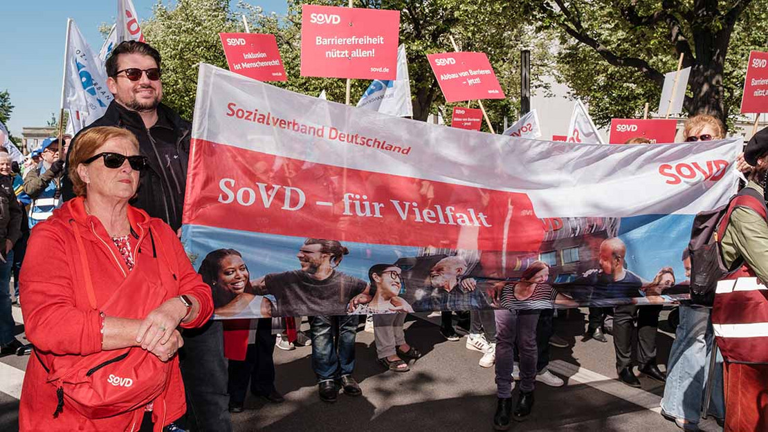 Eine Menschengruppe auf einer Demonstration trägt ein Transparent mit der Aufschrift "SoVD für Vielfalt". 