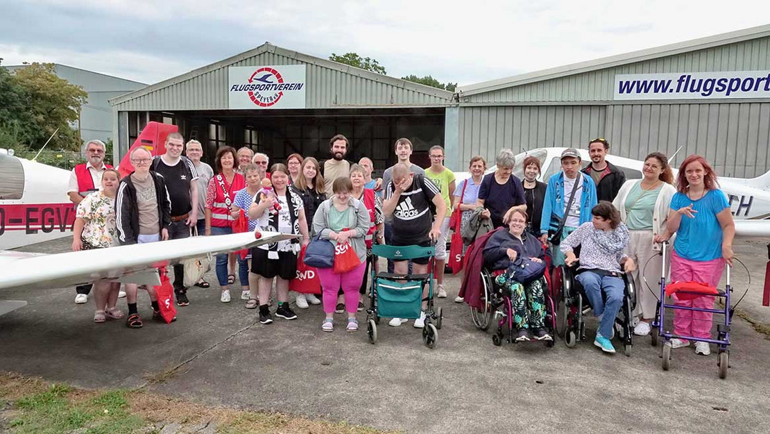 Gruppenfoto von Menschen vor einem Flugzeughangar. 