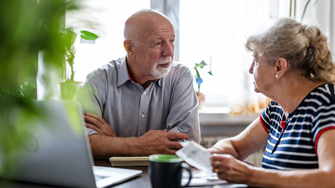 Älteres Ehepaar sitzt am Tisch und diskutiert.