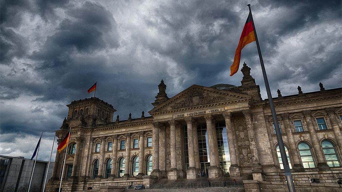 Eingang des Reichstags unter einem wolkenverhangenen Himmel. 