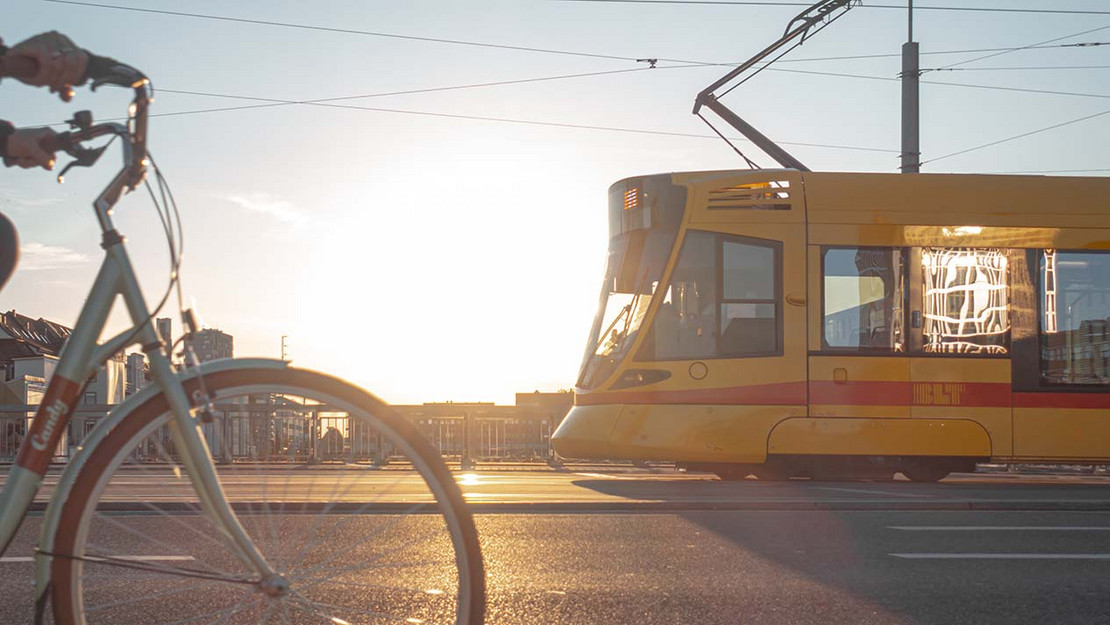 Fahrrad auf einer Straße. Im Hintergrund fährt eine Straßenbahn. 