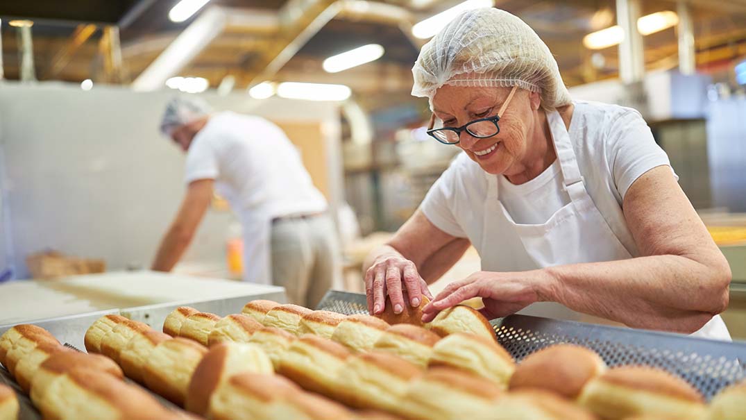 Ältere Frau arbeitet mit Backwaren.