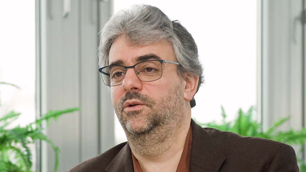 Mann sitzt in einem Büro und spricht.